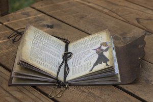open leather-bound journal to a page with text and a character rendering