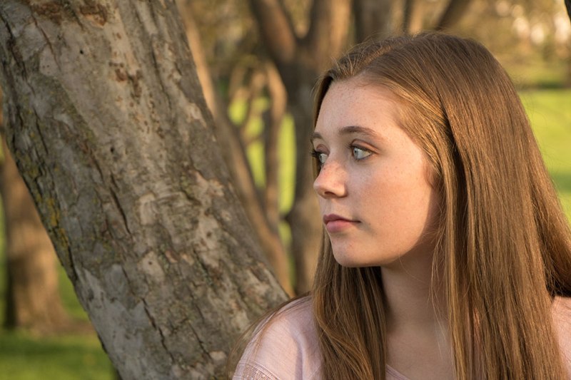 girl in front of a tree, looking to the left